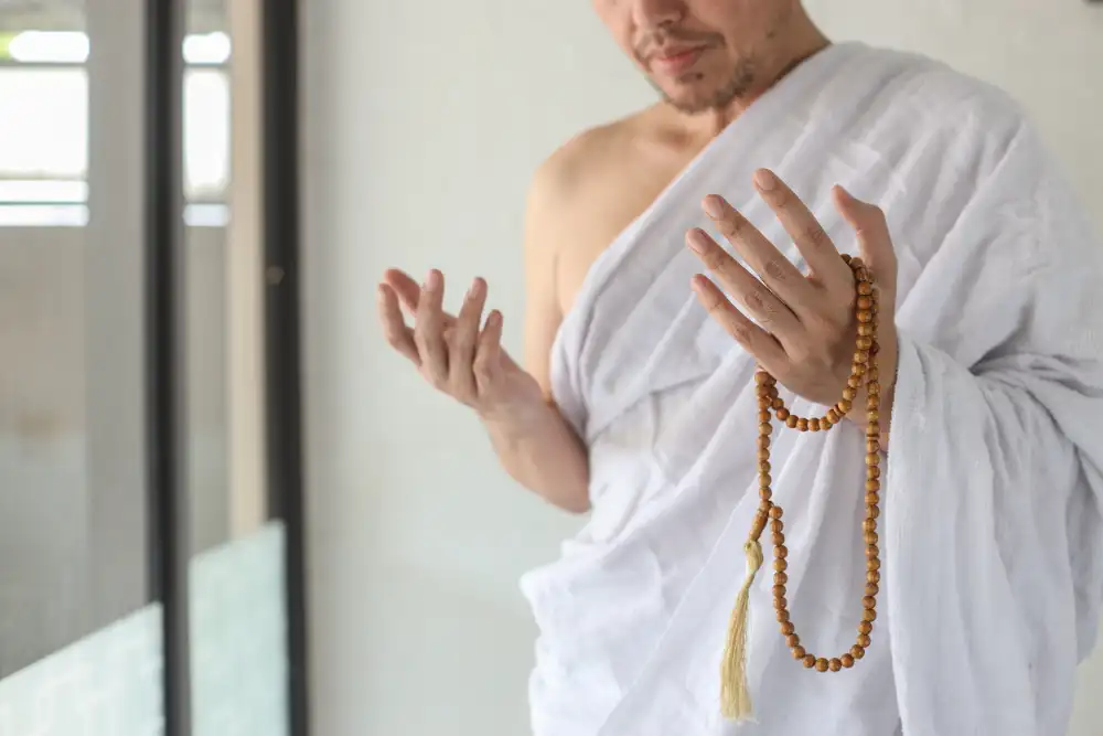 A pilgrim in ihram holding tasbih beads